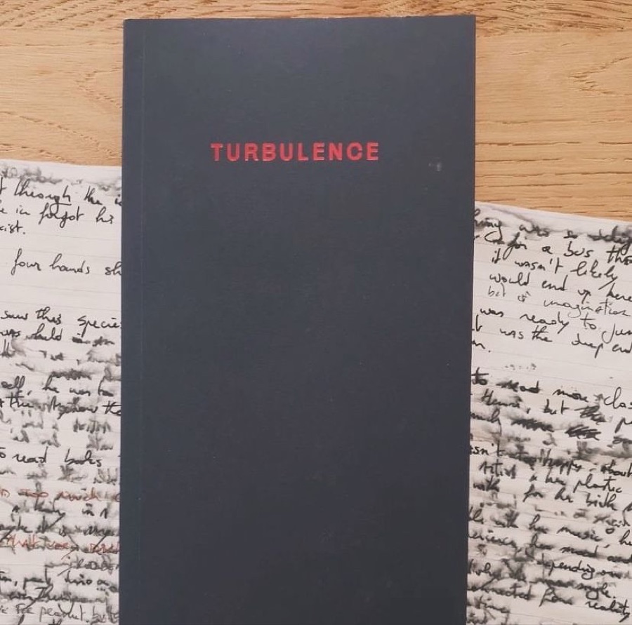 The black cover of Turbulence, its title in red, lying on handwritten pages